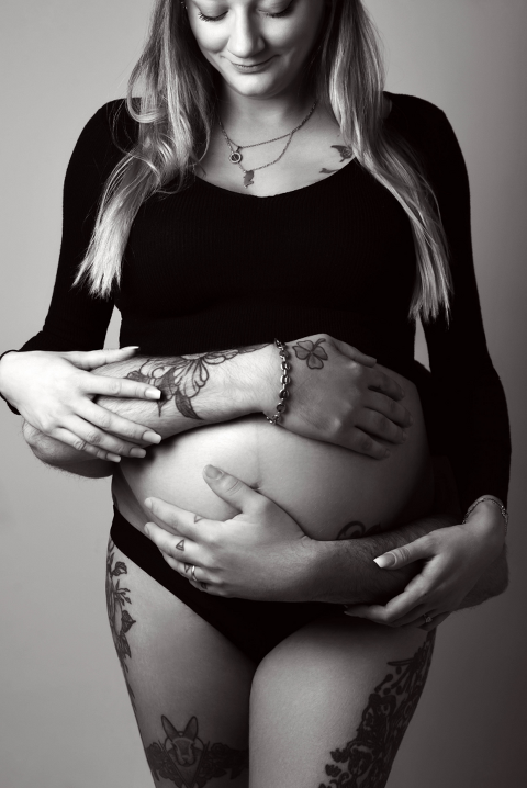 femme enceinte entourée par les bras de son mari