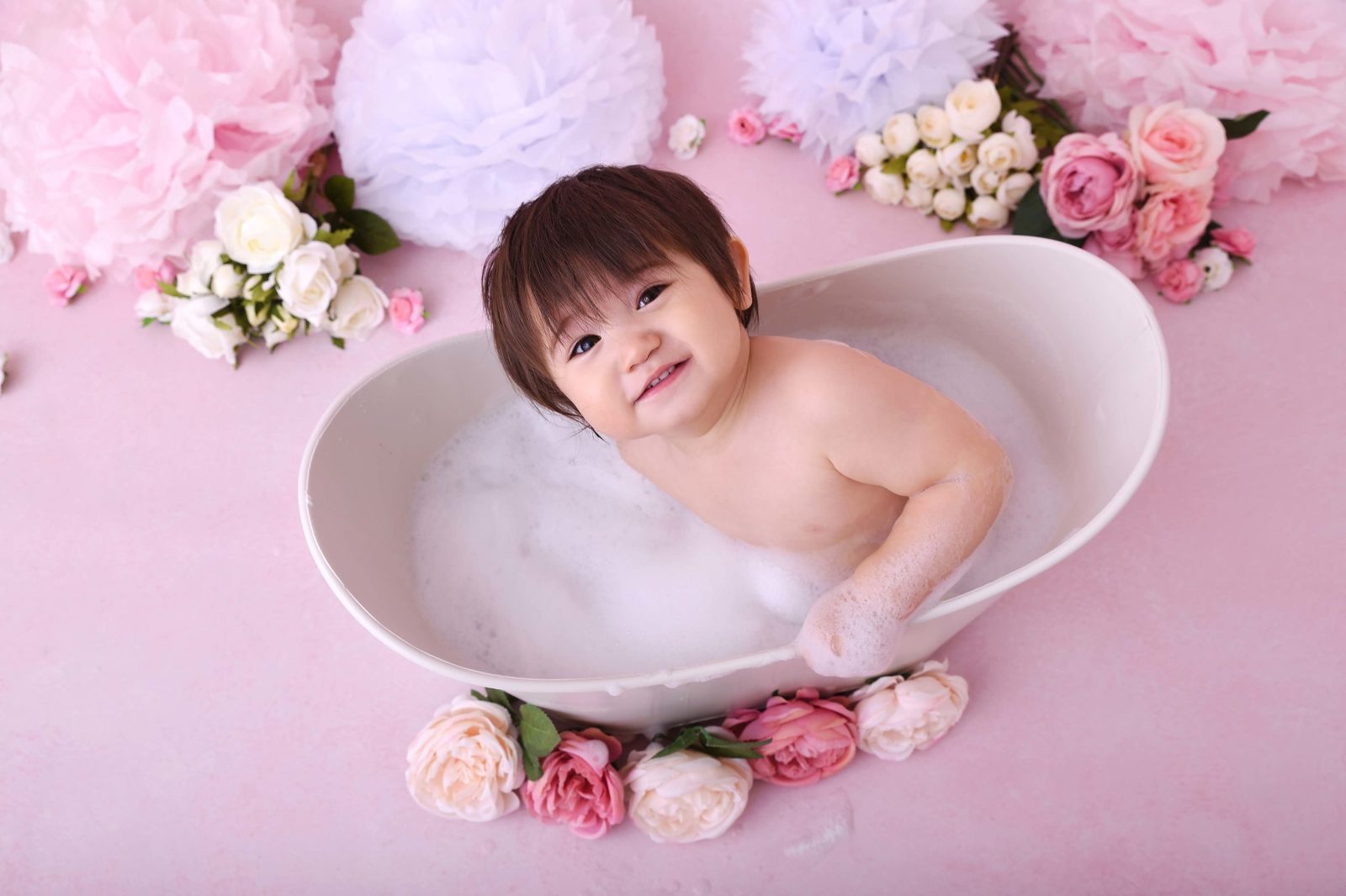 Bébé dans une baignoire entouré de fleurs