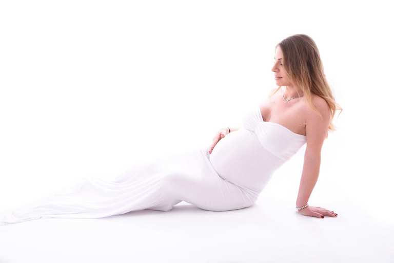 femme enceinte allongée en robe blanche
