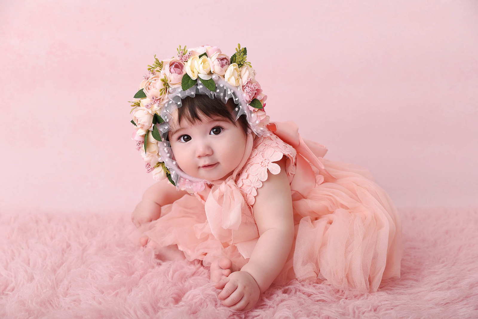 Bébé en robe rose avec un bonnet à fleurs